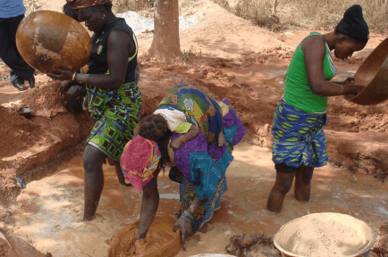 Three African woman trying to remove the impurities from the mud.