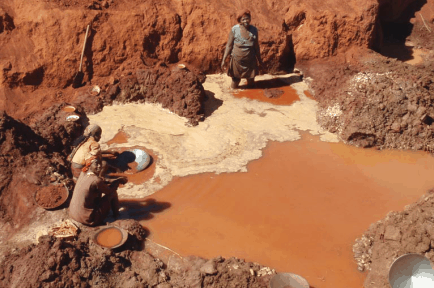 Woman in middle of muddy water trying to segregate water from mud.