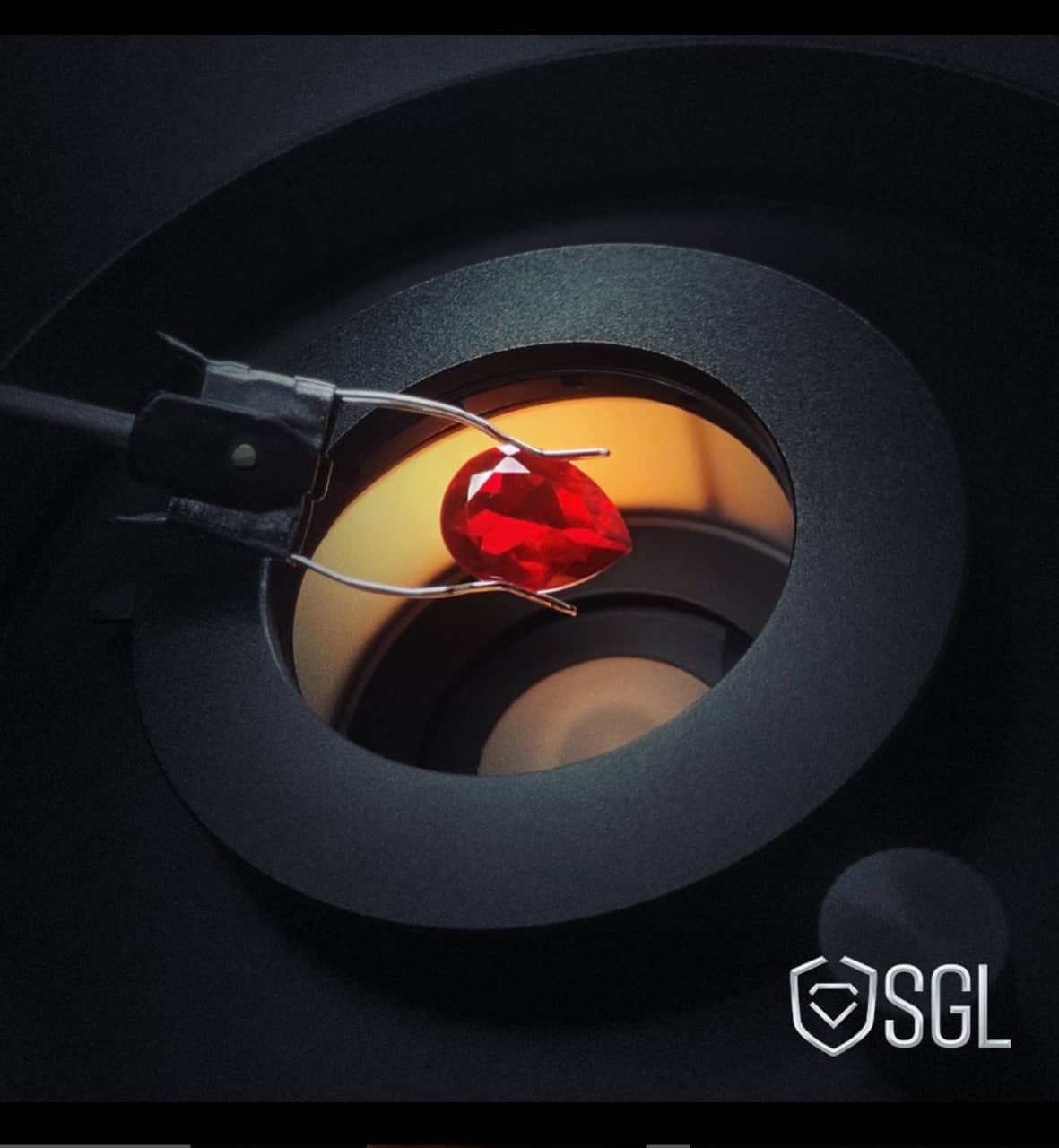 Red gemstone in a grading machine used on the London landing page for SGL.